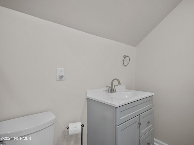 bathroom featuring vanity, toilet, and vaulted ceiling