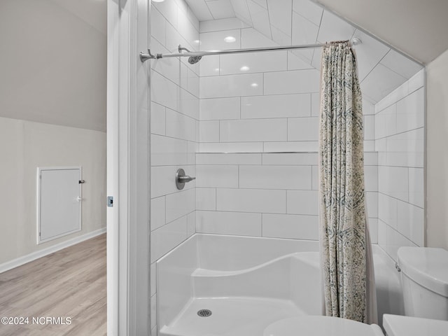 bathroom with hardwood / wood-style floors, vaulted ceiling, toilet, and curtained shower