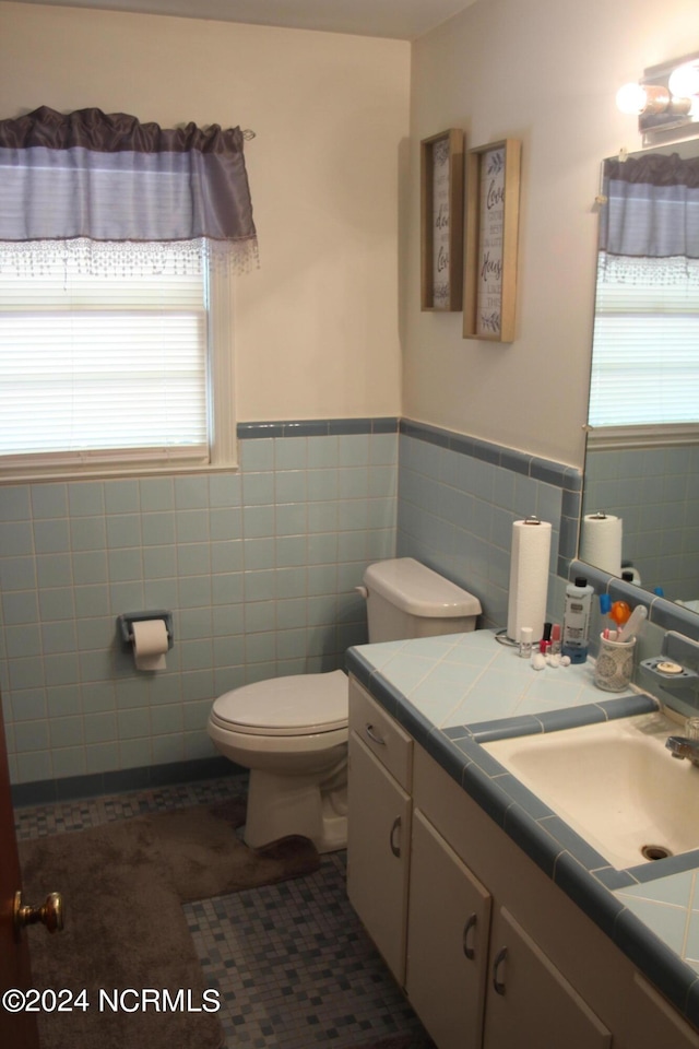 bathroom with tile patterned flooring, vanity, toilet, and tile walls