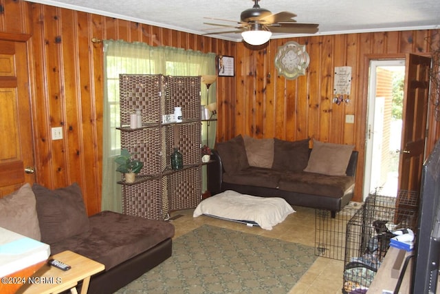 tiled living room featuring ornamental molding, a textured ceiling, ceiling fan, and wooden walls