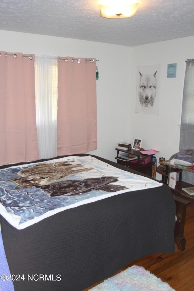 bedroom with a textured ceiling and hardwood / wood-style flooring