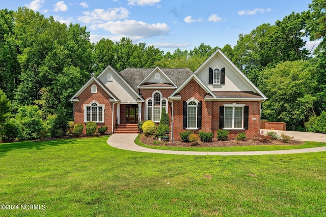 view of front of property featuring metal roof, brick siding, a standing seam roof, and a front yard