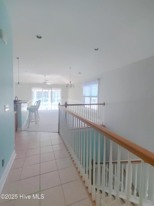 corridor featuring light tile patterned floors and an inviting chandelier