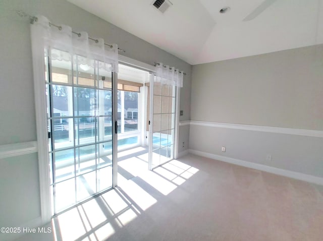 spare room featuring light carpet and vaulted ceiling