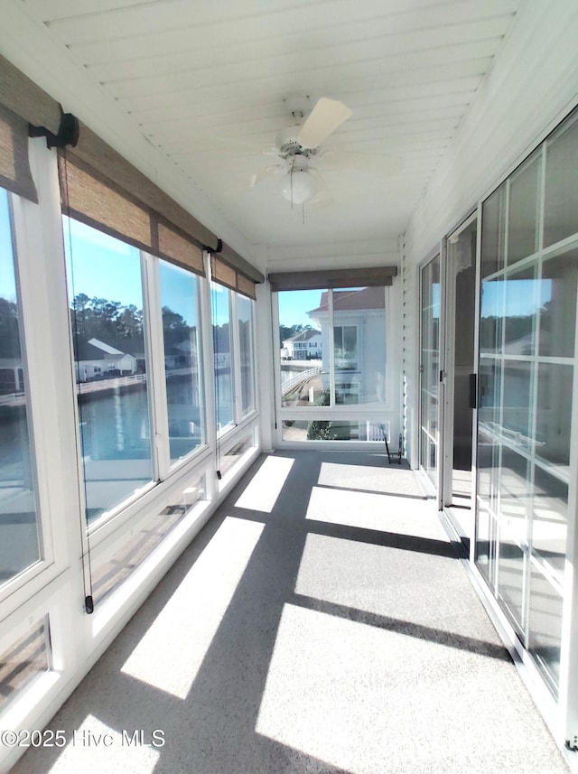 unfurnished sunroom featuring a water view and ceiling fan