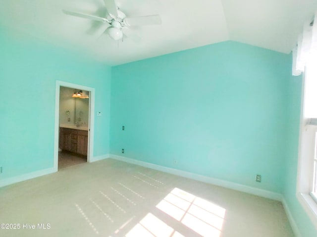 unfurnished bedroom with light colored carpet, ensuite bath, ceiling fan, and lofted ceiling