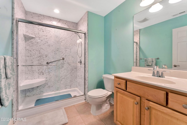 bathroom featuring tile patterned flooring, vanity, a shower with shower door, and toilet