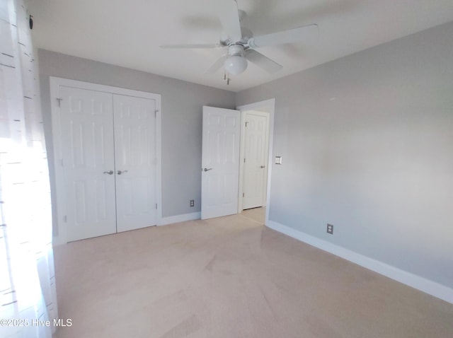 unfurnished bedroom with ceiling fan, light carpet, and a closet