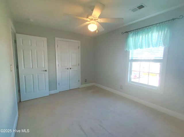 unfurnished bedroom with ceiling fan, light carpet, and a closet