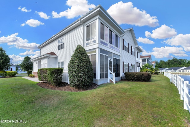 view of side of home with a sunroom and a yard