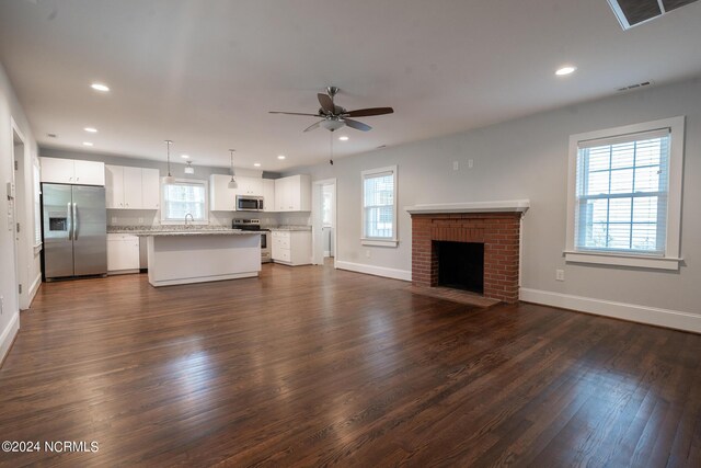 unfurnished living room featuring a healthy amount of sunlight, a fireplace, and dark wood-type flooring