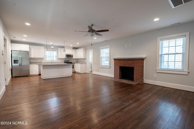 unfurnished living room featuring ceiling fan, dark hardwood / wood-style floors, sink, and a fireplace