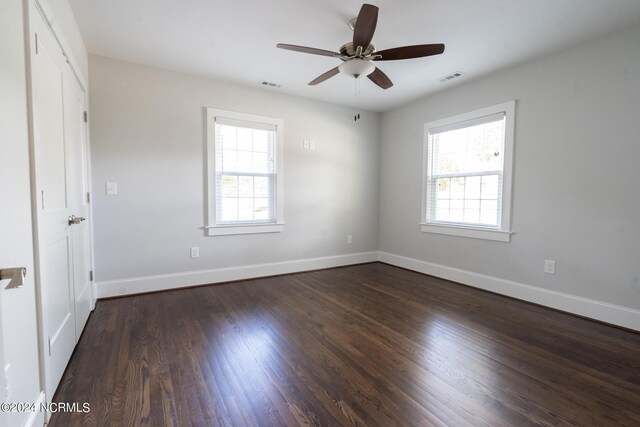 empty room featuring a wealth of natural light, wood-type flooring, and ceiling fan