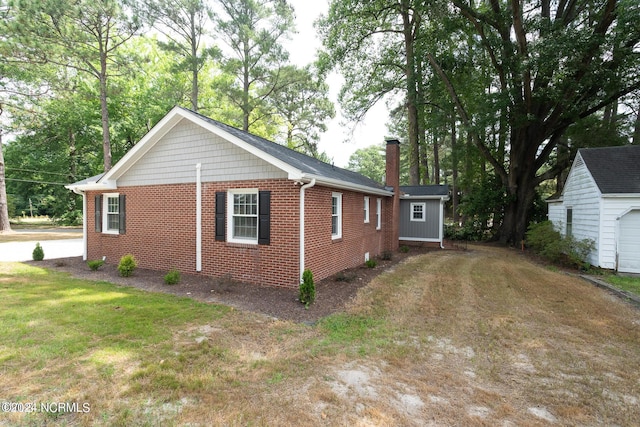 view of side of home with an outdoor structure and a lawn