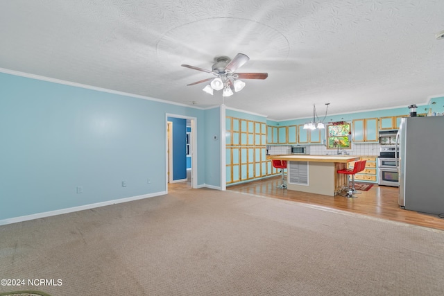 unfurnished living room featuring light colored carpet, ornamental molding, ceiling fan with notable chandelier, and a textured ceiling