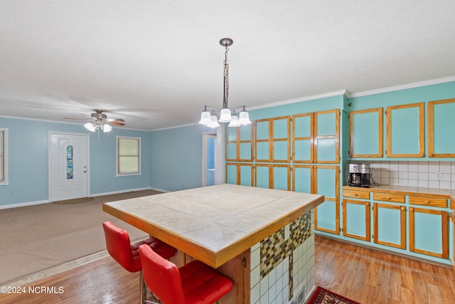 kitchen featuring pendant lighting, crown molding, decorative backsplash, and light wood-type flooring