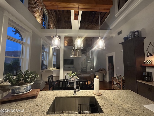 kitchen featuring decorative light fixtures, light stone countertops, and sink