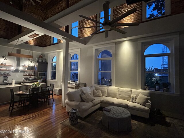 living room with a towering ceiling, hardwood / wood-style flooring, ceiling fan, and sink