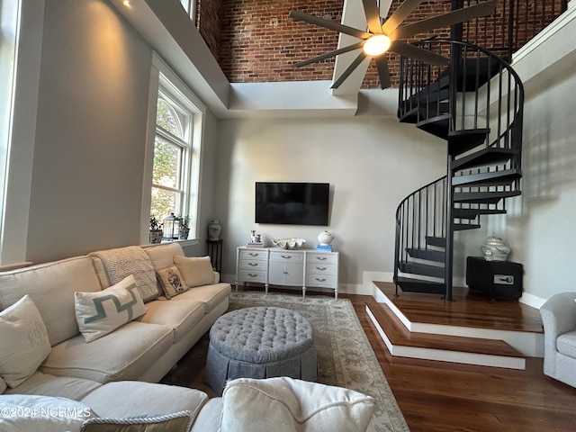 living room with ceiling fan, a towering ceiling, and dark hardwood / wood-style floors