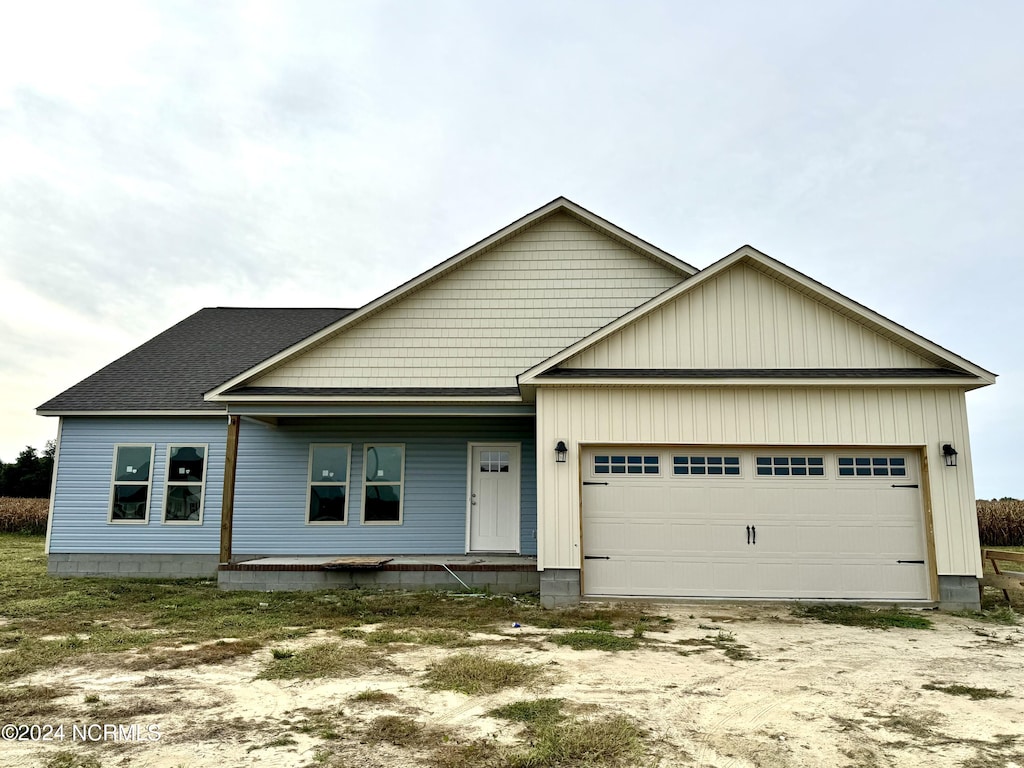 view of front of home with a garage, a porch, and roof with shingles