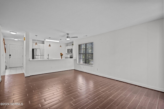 unfurnished living room featuring ceiling fan and sink