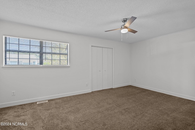 unfurnished bedroom featuring ceiling fan, a closet, dark carpet, and a textured ceiling