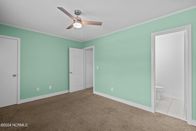 unfurnished bedroom featuring ensuite bath, ceiling fan, crown molding, and light colored carpet