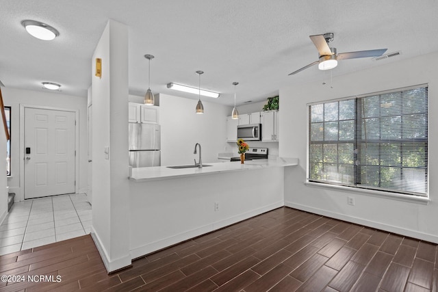 kitchen with sink, stainless steel appliances, kitchen peninsula, pendant lighting, and white cabinets