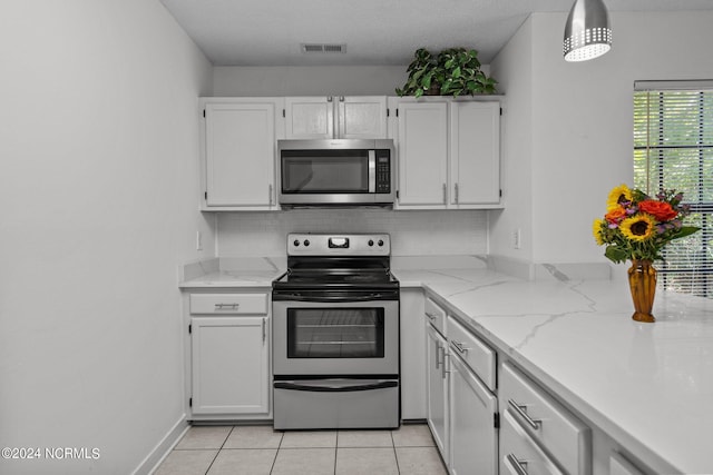 kitchen featuring stainless steel appliances, white cabinets, pendant lighting, a textured ceiling, and light tile patterned flooring