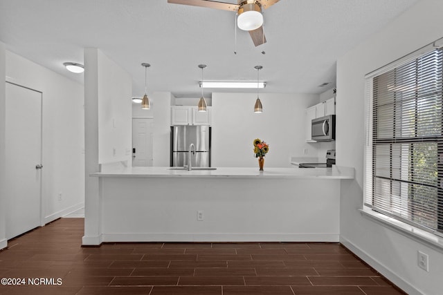 kitchen featuring white cabinets, decorative light fixtures, kitchen peninsula, and appliances with stainless steel finishes