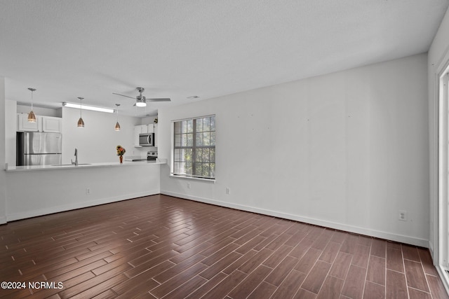 unfurnished living room with ceiling fan, sink, and a textured ceiling