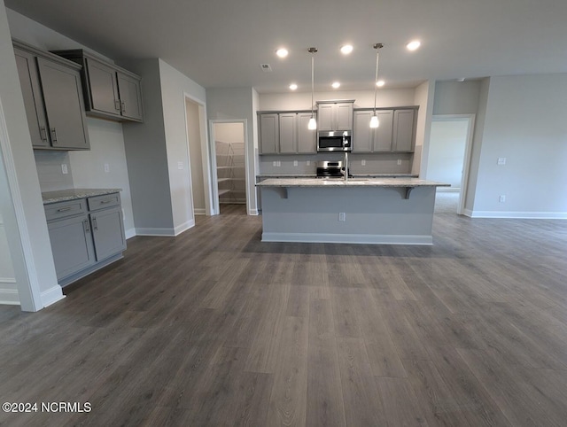 kitchen with gray cabinets, decorative light fixtures, light stone counters, and dark hardwood / wood-style flooring