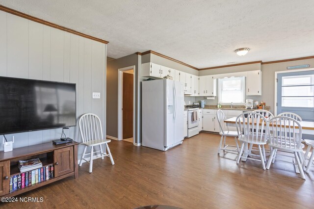 kitchen featuring wood-type flooring, a textured ceiling, white appliances, white cabinets, and ornamental molding