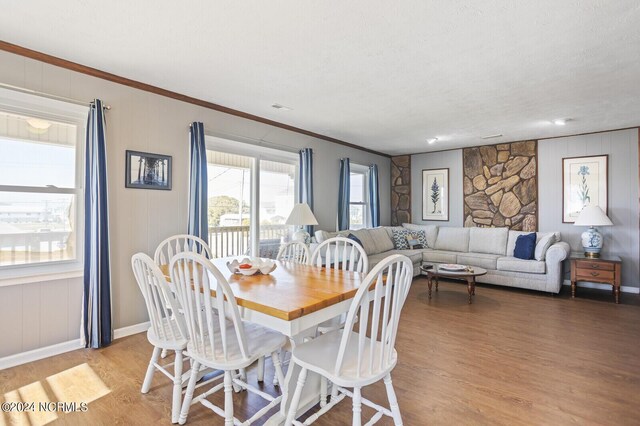 dining area featuring a textured ceiling, light wood-type flooring, and ornamental molding