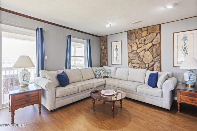 living room with wood-type flooring, ornamental molding, and a textured ceiling