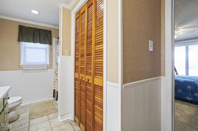 bathroom with vanity, toilet, a textured ceiling, and crown molding