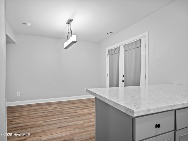 kitchen with gray cabinetry, hanging light fixtures, and hardwood / wood-style floors