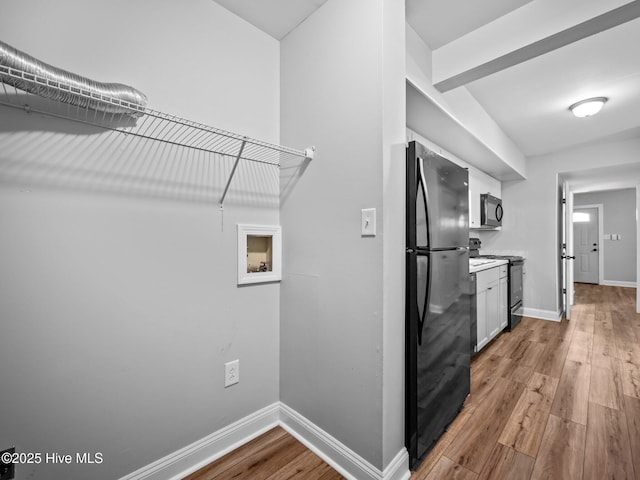 interior space with white cabinetry, black appliances, and light hardwood / wood-style floors