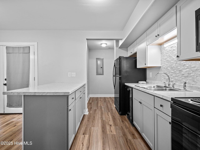 kitchen with light hardwood / wood-style floors, sink, a breakfast bar area, and black appliances