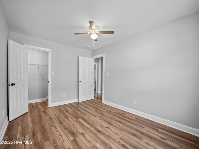 unfurnished bedroom featuring a walk in closet, light hardwood / wood-style floors, a closet, and ceiling fan