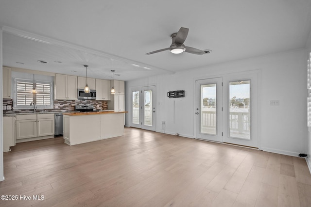 kitchen with wooden counters, decorative light fixtures, light hardwood / wood-style flooring, appliances with stainless steel finishes, and backsplash