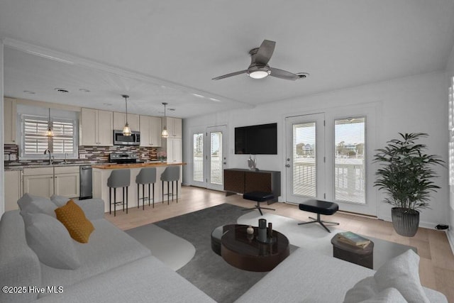 living room with ceiling fan, sink, and light wood-type flooring