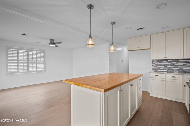 kitchen with hanging light fixtures, hardwood / wood-style floors, a center island, tasteful backsplash, and white cabinets