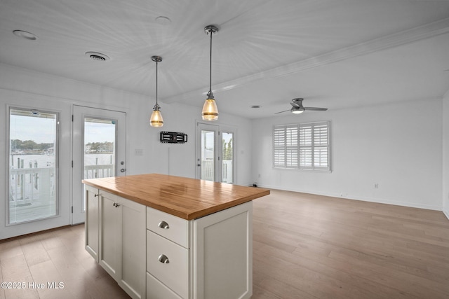 kitchen with butcher block counters, decorative light fixtures, light hardwood / wood-style flooring, a kitchen island, and white cabinets