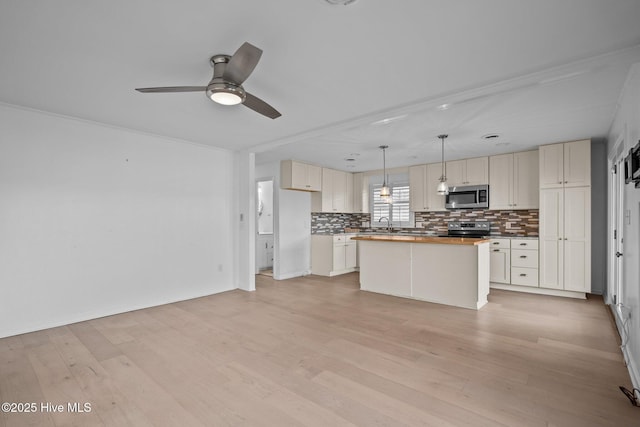 kitchen featuring appliances with stainless steel finishes, hanging light fixtures, a center island, light hardwood / wood-style floors, and decorative backsplash