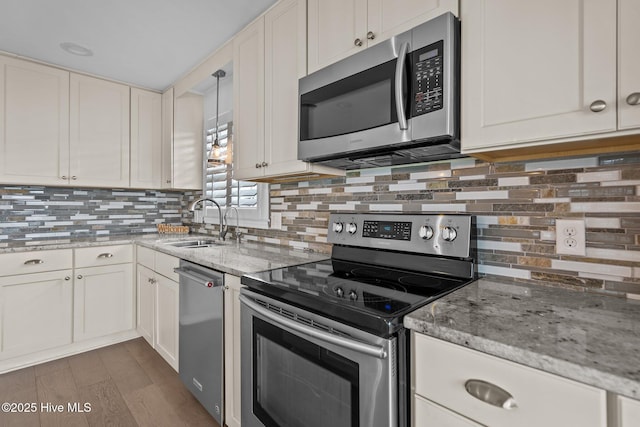 kitchen featuring sink, appliances with stainless steel finishes, light stone counters, white cabinets, and decorative backsplash