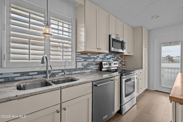 kitchen with sink, white cabinets, backsplash, stainless steel appliances, and light stone countertops