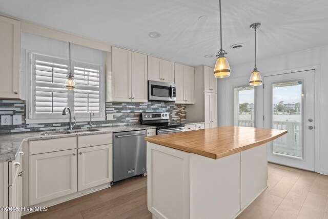 kitchen with sink, a center island, pendant lighting, stainless steel appliances, and white cabinets