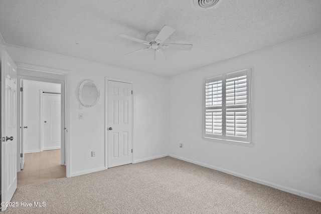 unfurnished bedroom featuring ceiling fan, light colored carpet, and a textured ceiling