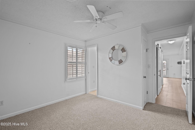 spare room featuring ceiling fan, light colored carpet, and a textured ceiling